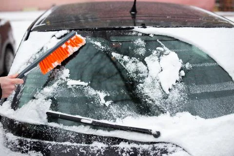 Winter problems with the car. A man cleans the car from snow with a brush Stock Photos