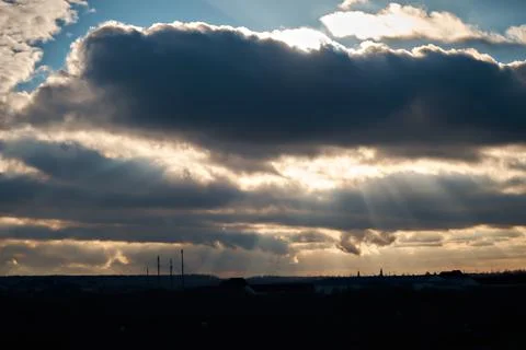 The winter rays of the sun break through thick gray clouds. Stock Photos