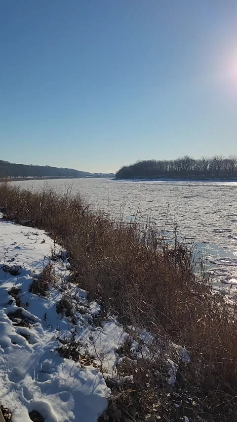 Winter River with Drifting Ice and Snowy Riverbank Foreground Stock Footage 330220576