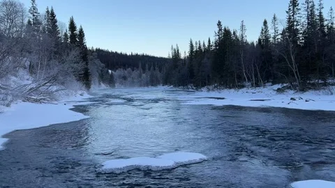 Winter river flowing through a snow-covered forest in northern Sweden Stock Footage 326157381
