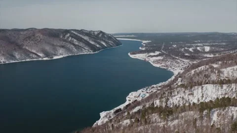 Winter river flows between snow-capped mountains, landscape shot from the air 库存影片 141408853
