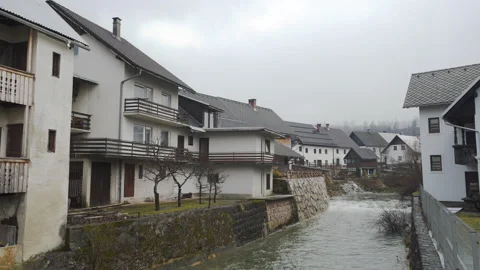 Winter river flows through houses on gray day in Bohinj, Slovenia Video stock 134497333