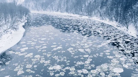 Winter river ice flow, snow falling, aerial view Video stock 101093993