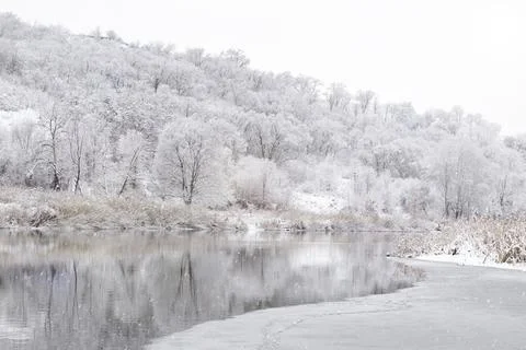 Winter river in a snowy forest in the rays of the sun and falling snow. Stock Photos