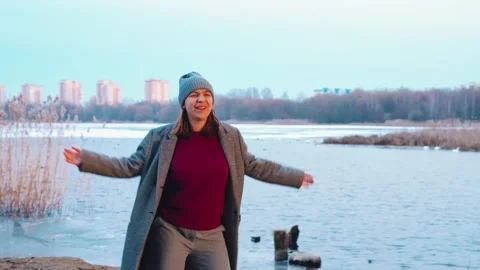 Winter riverside dancer woman dancing by frozen river during sunset wearing coat Stock Footage 324965706