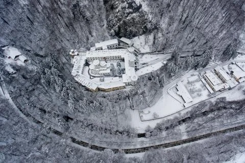 Winter road and monastery surrounded by trees shot from a drone above Foto stock
