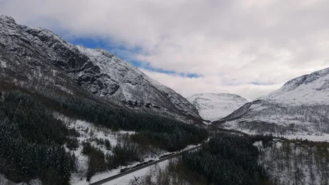 Winter Road Cutting Through Snowy Norwegian Valley with Forested Slopes Vidéo 334743198