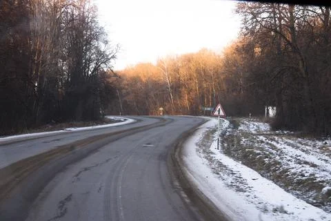 Winter road in the forest with a red warning sign on it. Stock Photos