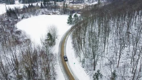 Winter Road Trip Car Navigating a Snowy Landscape Through a Forest, Aerial View Stock Photos
