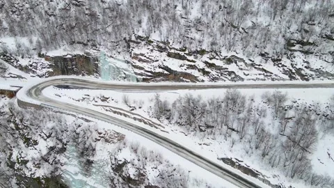 Winter Road Winding Through Snow Covered Mountains and Frozen Waterfalls in Norw Video stock 315728230