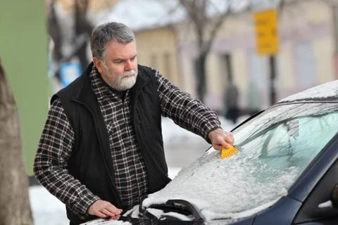 Winter scene, driver cleaning windshield of car 写真素材