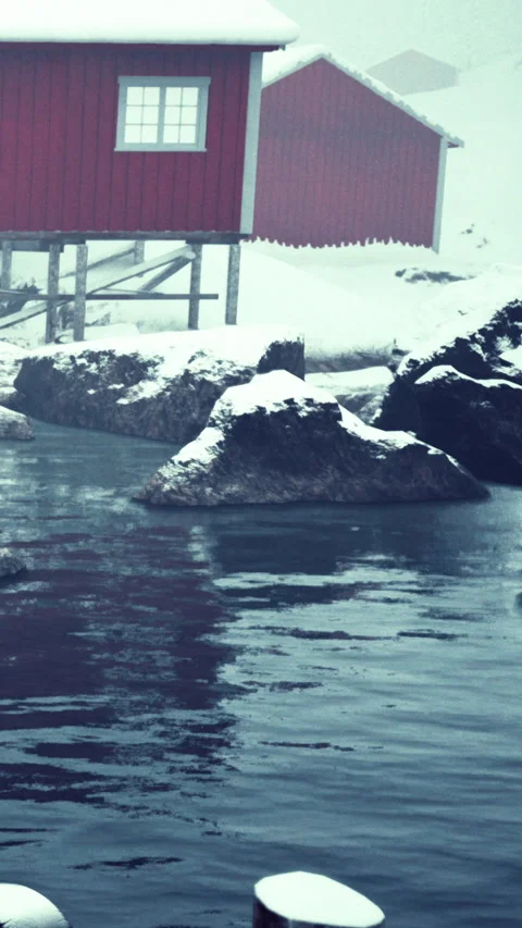 Winter scene with red cabin and rocks in cold water near the shore Stock Footage 340642615