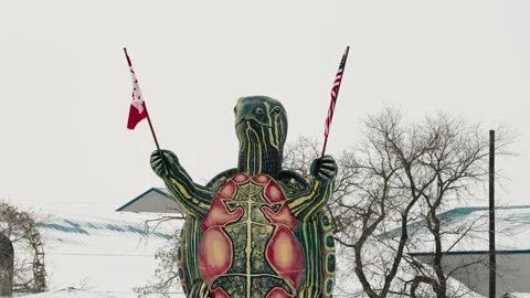 A winter scene shows a tall turtle figure lifting two nations flags Stock Footage 296574935
