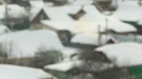 Winter scene of snow falling over village landscape, rooftops of houses covered Stock Footage 344846860