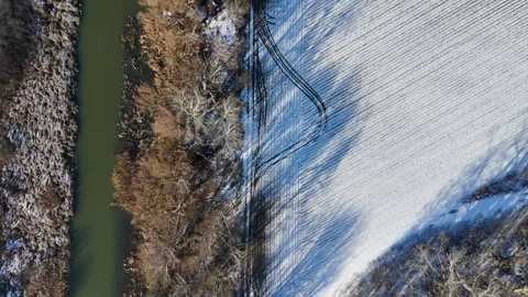 Winter Shadows: Aerial Perspective of Snow-Covered Farmland and Riverbank Stock Footage 281114051