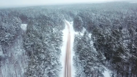 On the winter snow-covered road among the frozen forest car rides. The drone Stock Footage 101656400