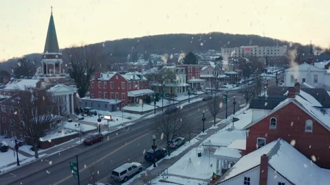 Winter snow falls on quaint cozy America town. Smoke from chimney during Video stock 157429186