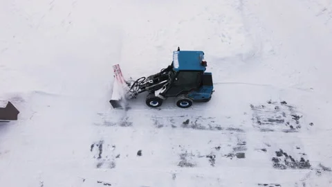 Winter snow removal from sidewalks. A mini tractor shovels snow onto the side of Видео 169461678