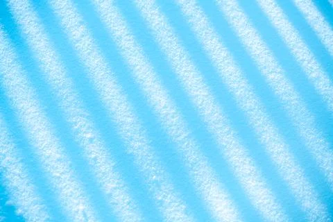 Winter snow surface showing intriguing abstract patterns of diagonal shadow Stock Photos