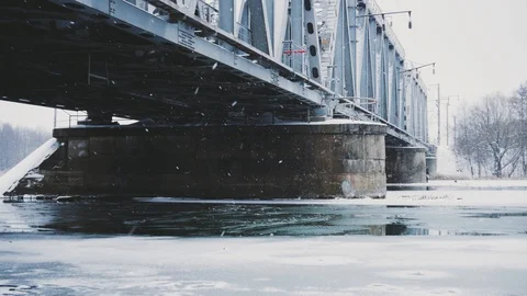 Winter snowfall on the background of the railway bridge on the river Video stock 99591398