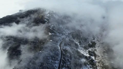 Winter Snowy Mountain Summit Road Winding Through Rugged Peaks Aerial Stock Footage 320447584