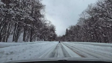 Winter snowy road driving slight left curve following car forest Japan Stockbeeldmateriaal 333204971
