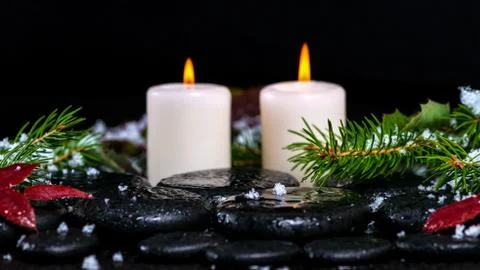 Winter spa concept of evergreen branches with drops, snow,  candles on zen ba Stock Photos
