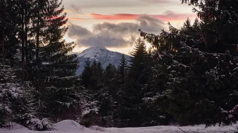 Winter in the spruce forest. At dusk, clouds overflow the rocky mountains. 4K Stock Footage 170692787