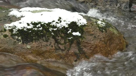 Winter stream flowing fast around snow covered boulder Stock Footage 45532327