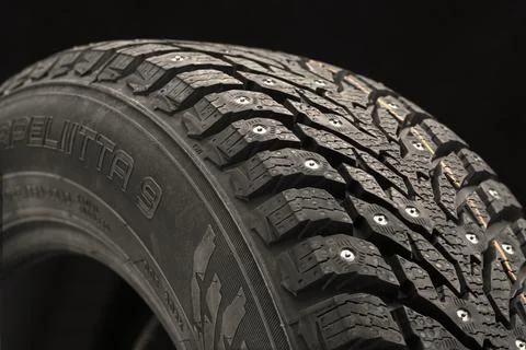 Winter studded tire side view close-up on a black background safety, Stock Photos