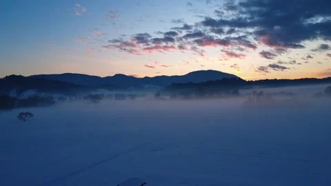 Winter Sunset Drone Rising Through Fog Above Snowy Landscape Stock Footage 329886506