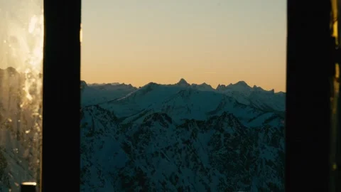 Winter Sunset View over Snowy Alpine Mountain Peaks from a Cabin Window 库存影片 331170323