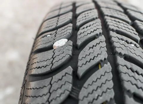 Winter tire tread with a small stone stuck in the groove Stock Photos