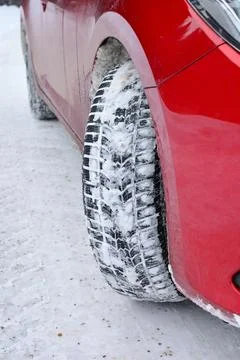 Winter tyre, red car, empty snowy road Fotos de archivo