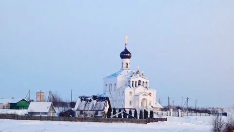 Winter view of a church surrounded by snow and buildings in a rural area during Stock-Footage 328138741