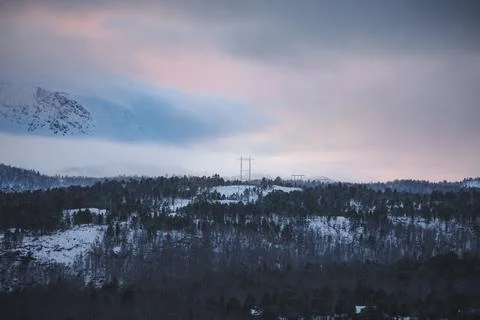 Winter view of power lines crossing snowy forest near Malangen Fjord in Tro.. Stock Photos