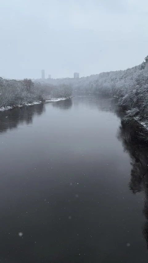 Winter view of river from bridge during snowfall in Vilnius, Lithuania. Vertical Stock Footage 260076869