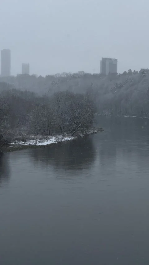 Winter view of snowy river from bridge during snowfall in Vilnius. Vertical Stock Footage 260076925