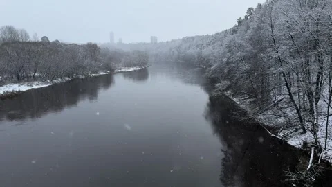 Winter view of snowyr iver from bridge at park during snowfall in Vilnius Stock Footage 260076918