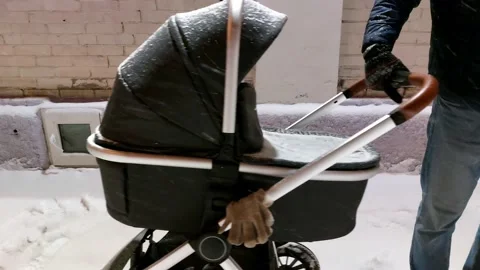 Winter walk with a baby in a stroller. A man rocks a stroller. Stock Footage 229877333