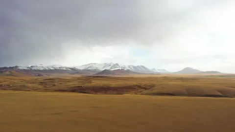 Winter withered grasslands and distant snowcapped mountains Stock Footage 243065062