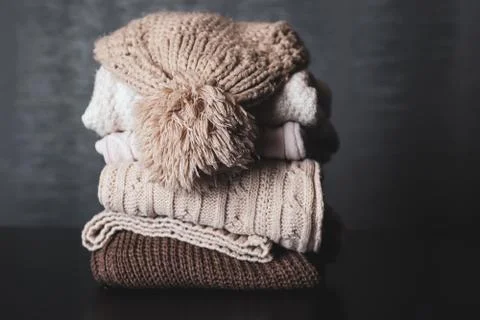 Winter woolen cap on sweaters piles on a desk at home Stock Photos
