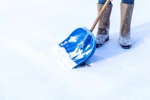 Winter work on the site: we clean the snow. Blue shovel for snow removal on t Stock Photos