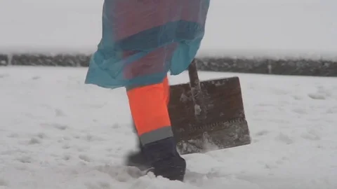 Winter. A worker with a shovel in overalls clears snow falling during a snowfall Stock Footage 83775318