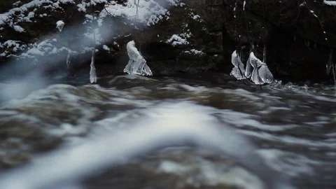 Wintry river flows fast after a spring thaw, and lumps of ice dangling on bra Stock Footage 126594819