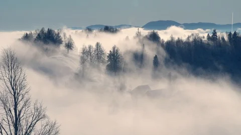 Wintry scene of snow covered landscape and fog pouring over village Stock Footage 121478492