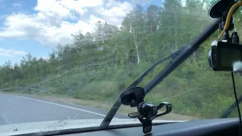 Wipers clean the windshield against the blue sky in the clouds Stock Footage 124791696