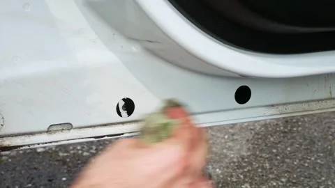 Wiping away tar from the inside of a white van door with a yellow microfiber Stock Footage 321068975