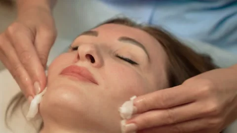 Wiping client face with cotton pads before beauty procedure. Cleaning facial Stock Footage 301992534