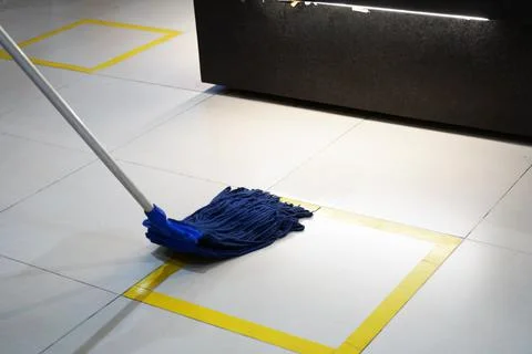 Wiping a floor with yellow stripes, using a blue mop Stock Photos
